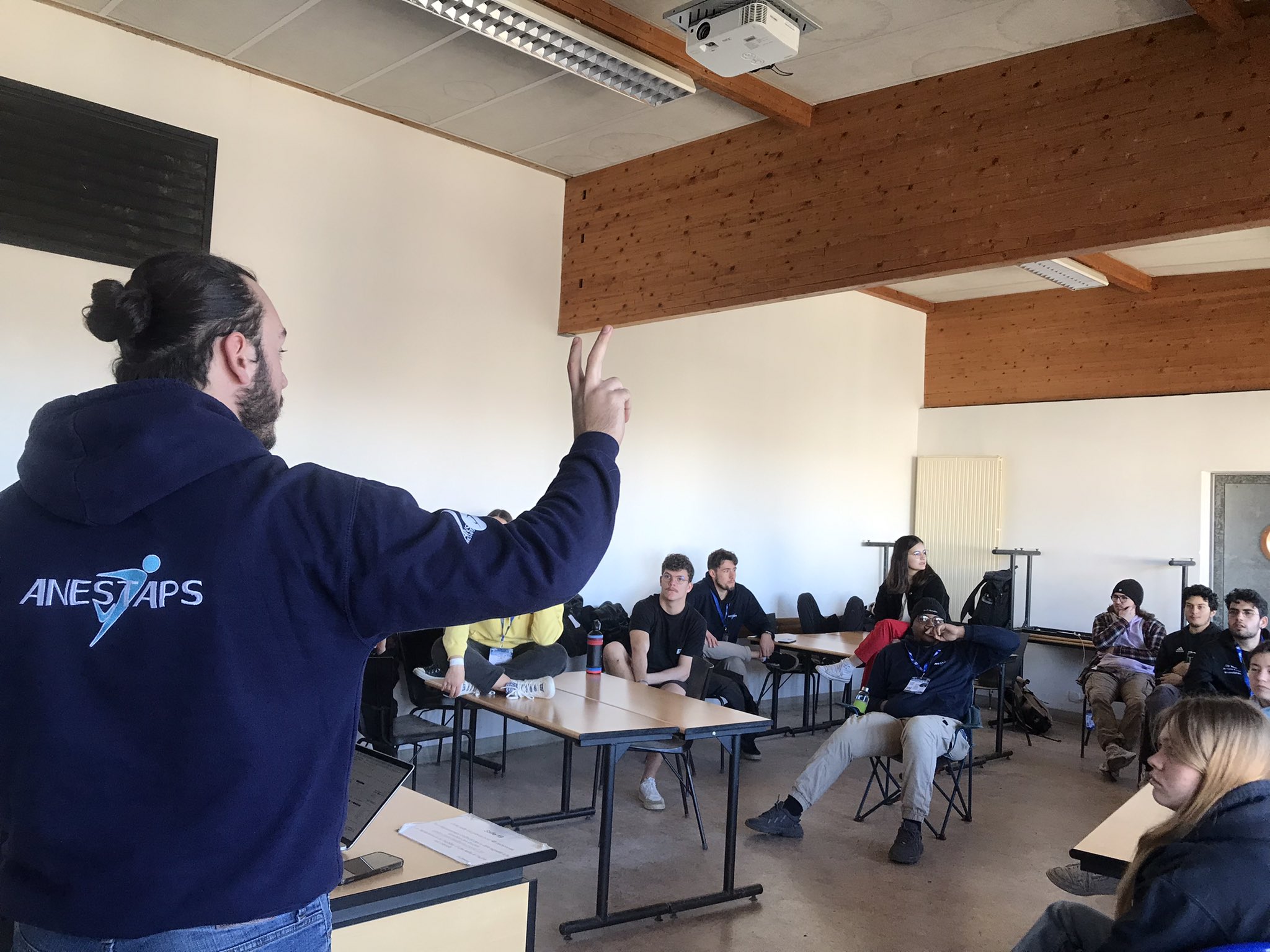WEAS 2023 un homme au premier plan avec un pull de l'ANESTAPS qui s'adresse à des étudiants